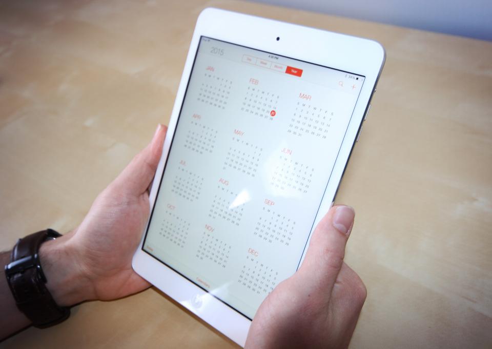 To hænder holder en ældre iPad mini med kalenderen åben