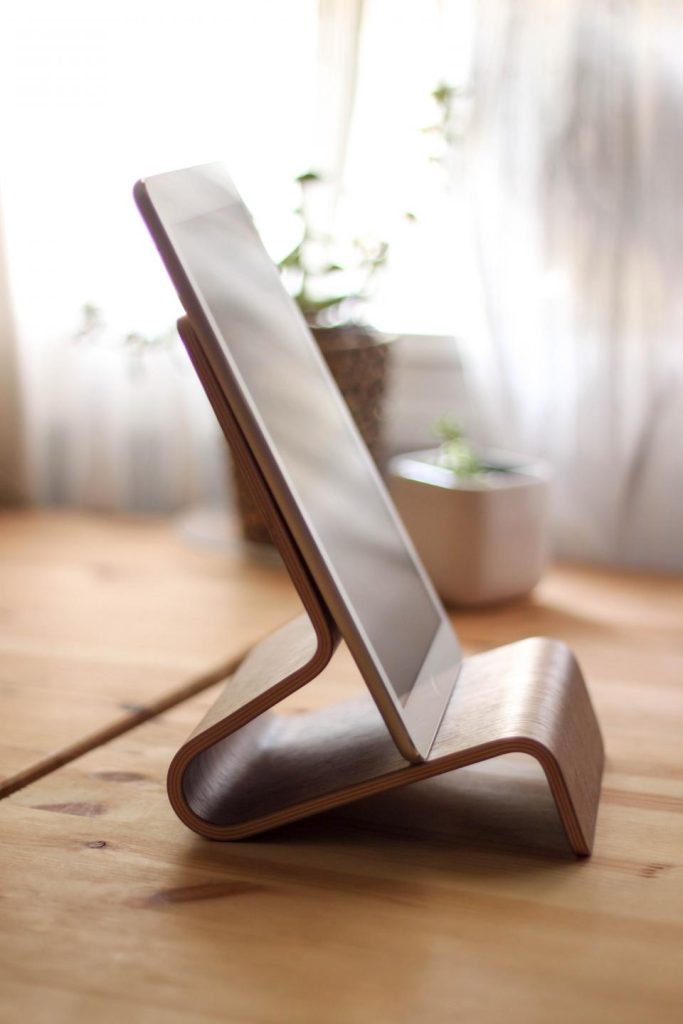 En iPad i en stander af træ på et bord ved vinduet